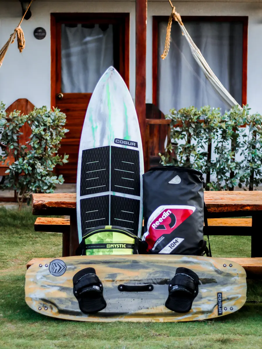 Pranchas de kite e de surfe encostadas numa mesa de madeira na frente de uma casa