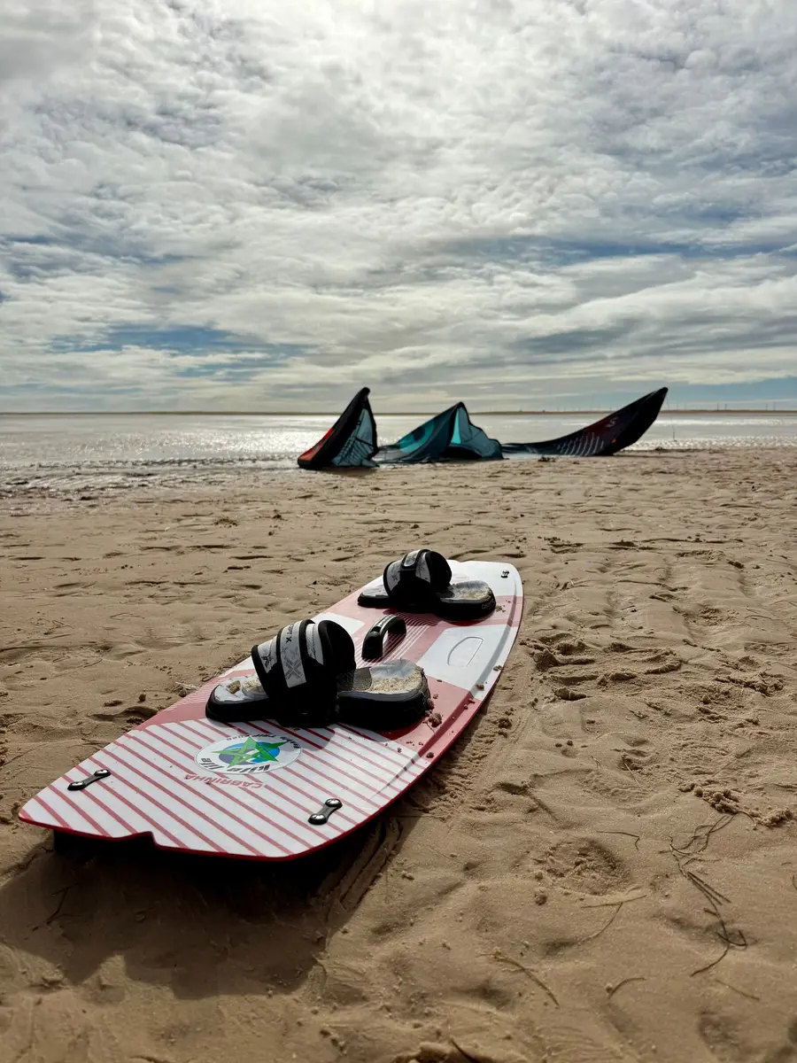 Prancha de kite na areia, com duas pipas estendidas mais atrás